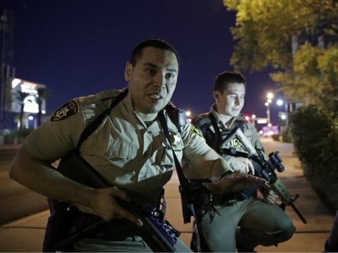 Police officers advise people to take cover near the scene of a shooting near the Mandalay Bay resort and casino on the Las Vegas Strip, Sunday, Oct. 1, 2017, in Las Vegas. 